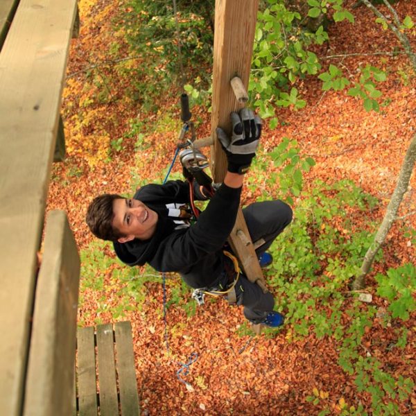 a man standing on top of a wooden fence