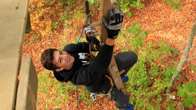 a man standing on top of a wooden fence