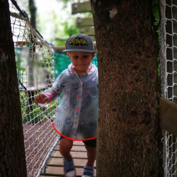 a young boy standing next to a fence